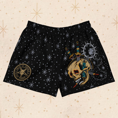 Front view of Overkill Tattoo Women’s Gym Shorts featuring an all-over celestial star pattern and a bold American Traditional tattoo-style skull with weapons.